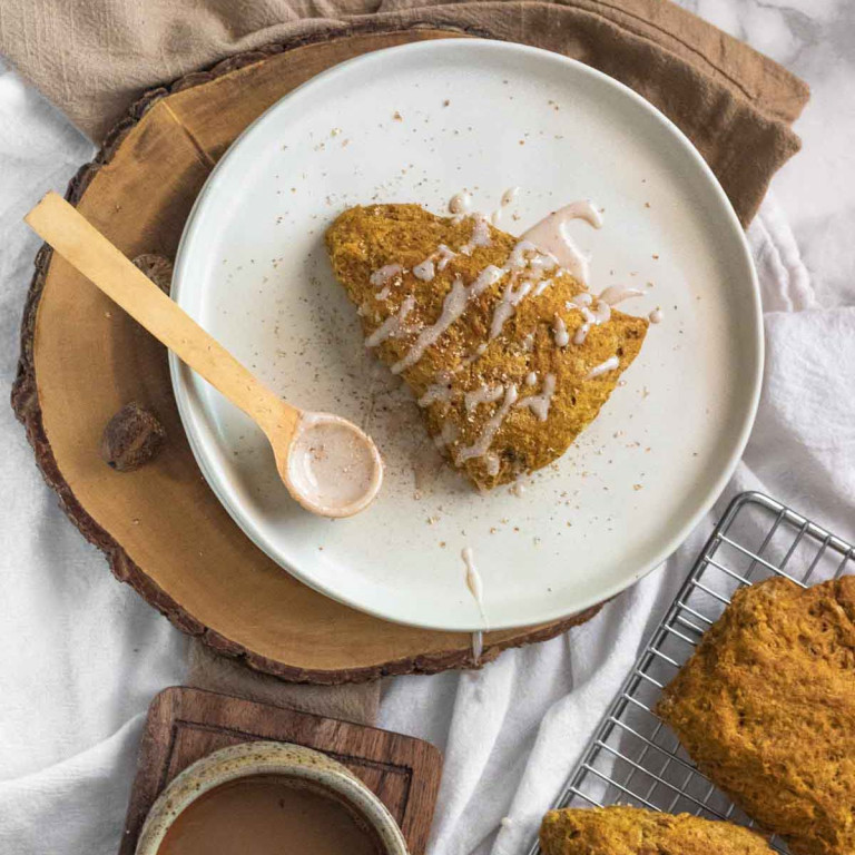 A scone on a plate with drizzled glaze.