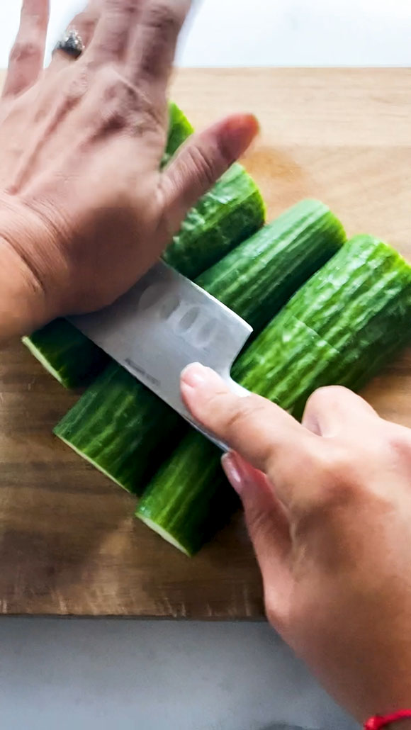 Smashing cucumbers with the side of a knife.