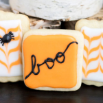 An orange cookie with the word boo in black icing.