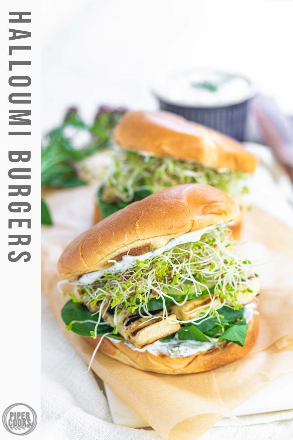 A burger bun stuffed with spinach, grilled halloumi, cucumbers, alfalfa sprouts, and a yogurt spread.,