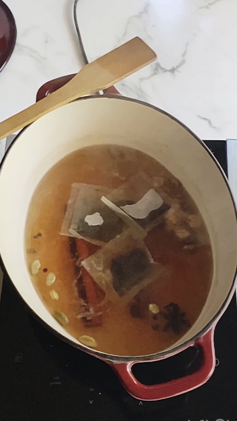 Tea bags floating in a dutch oven with water and spices.