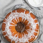 A whole bundt cake with icing and coconut on top and a text title.