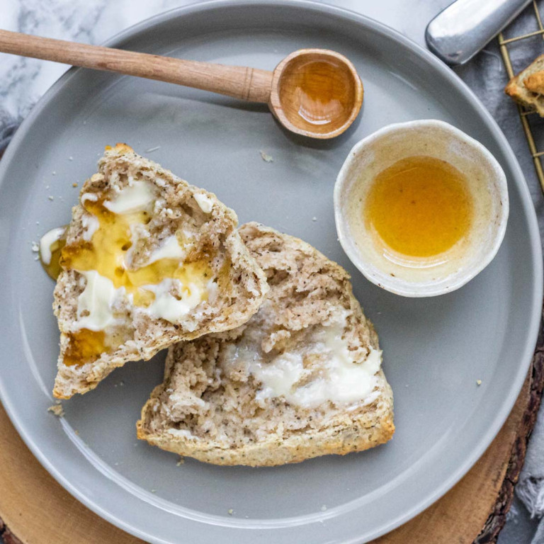 A halved scone with butter and honey on it.