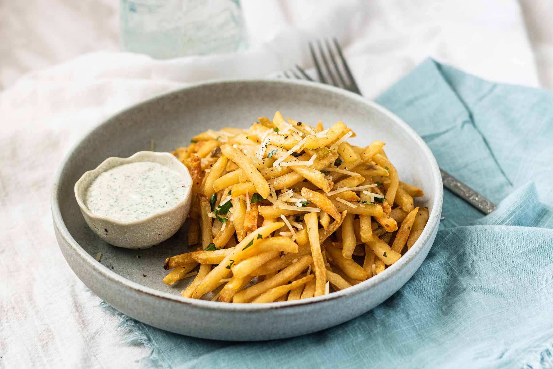 Fries on a plate garnished with parmesan cheese and parsley.