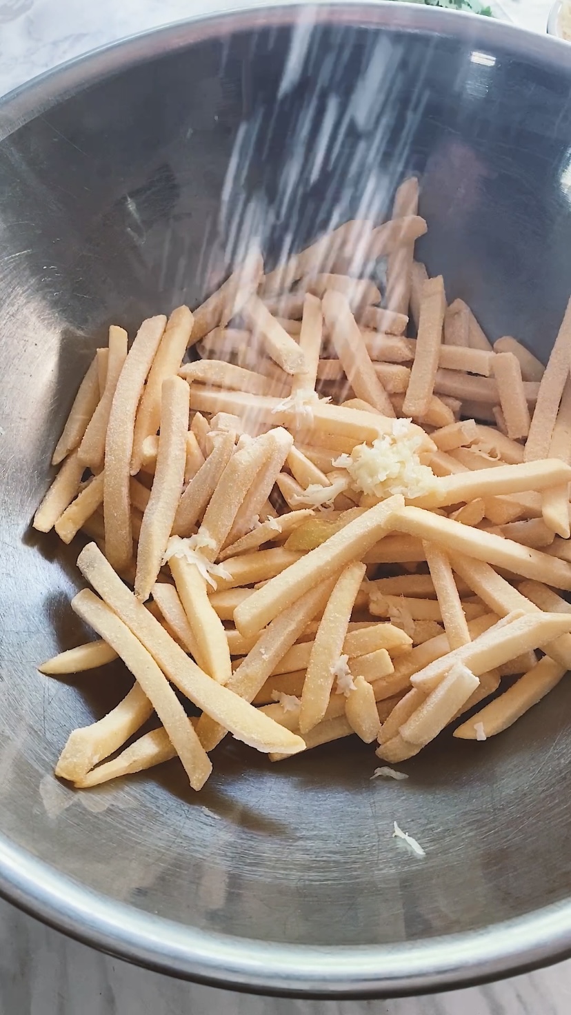 Salting frozen fries in a bowl.