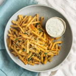 Fries on a plate garnished with parmesan cheese and parsley.
