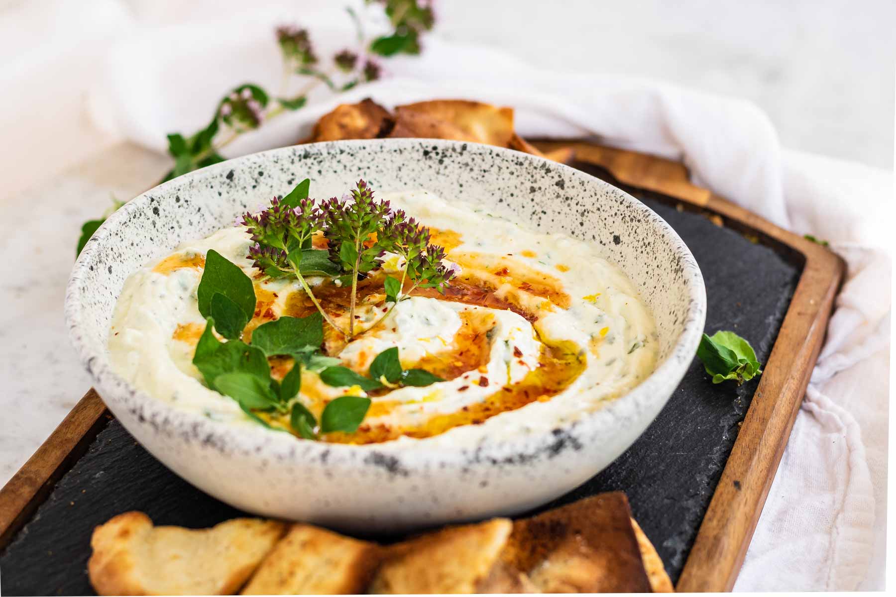 Whipped ricotta dip in a bowl with fresh oregano and hot honey on top.