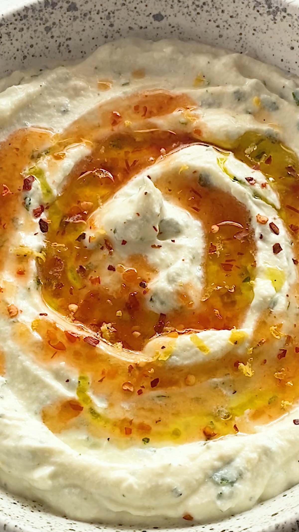 A close up of whipped ricotta with hot honey and crushed red pepper on top.