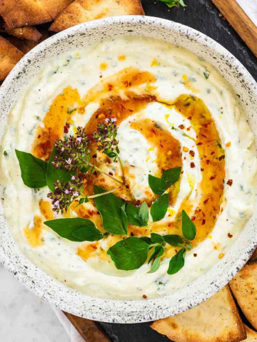 Whipped ricotta dip in a bowl with fresh oregano and hot honey on top.