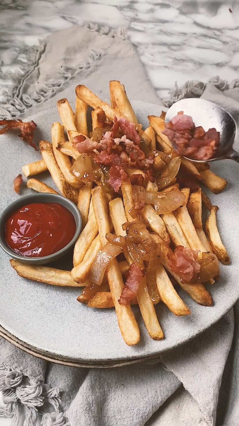 Adding bacon to fries.