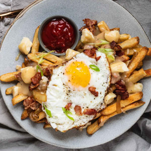Fries topped with cheese curds, gravy, bacon, and an egg.