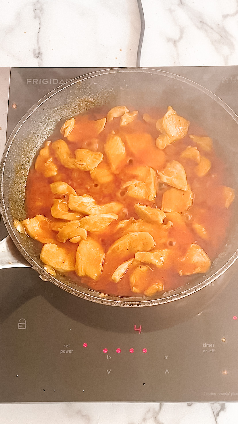 Chicken cooking in a buffalo sauce.