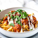 Fries with butter chicken sauce on top with text title.