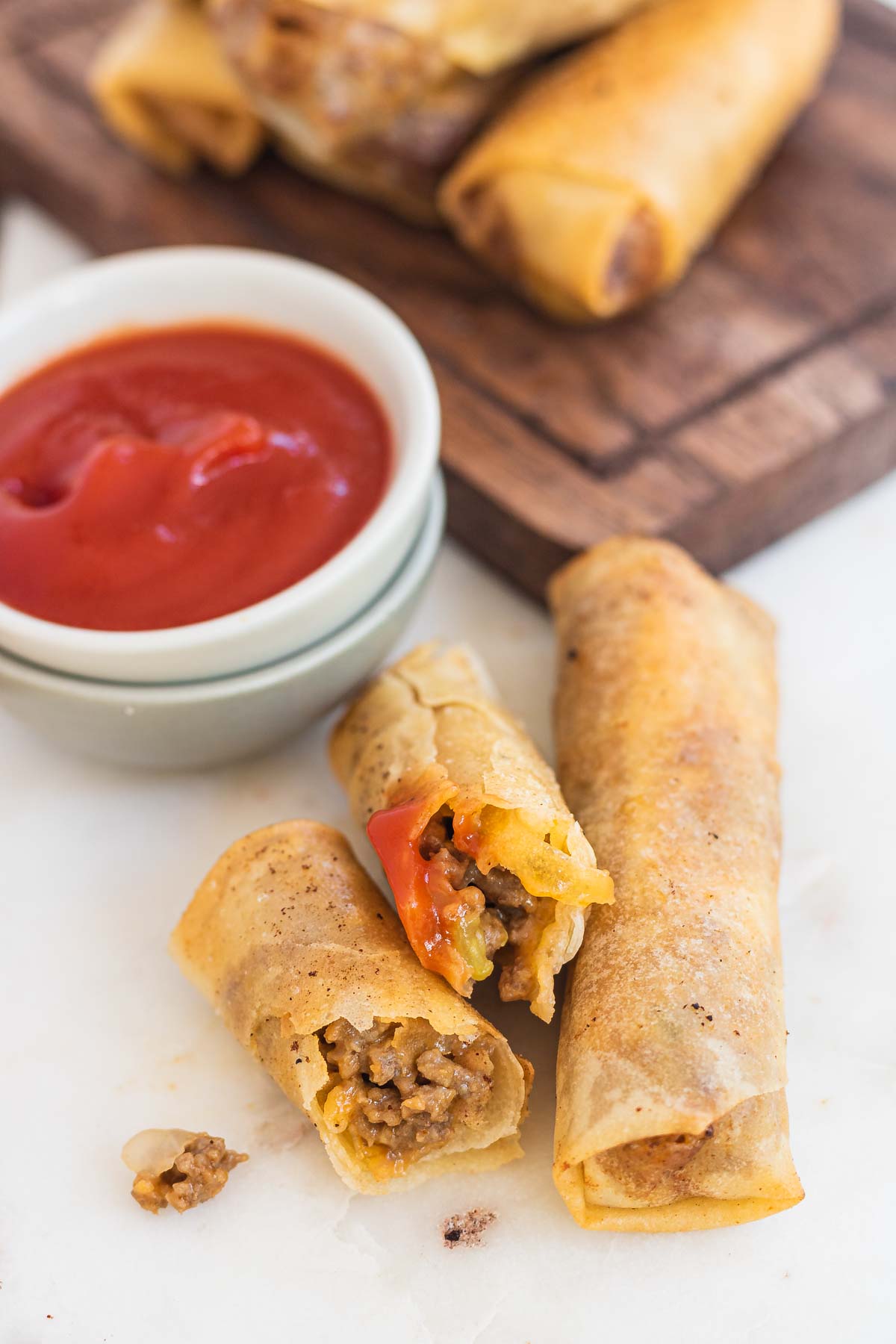 Cheeseburger spring rolls cut in half to show the filling.
