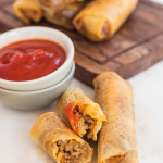 Cheeseburger spring rolls cut in half to show the filling with a text title.