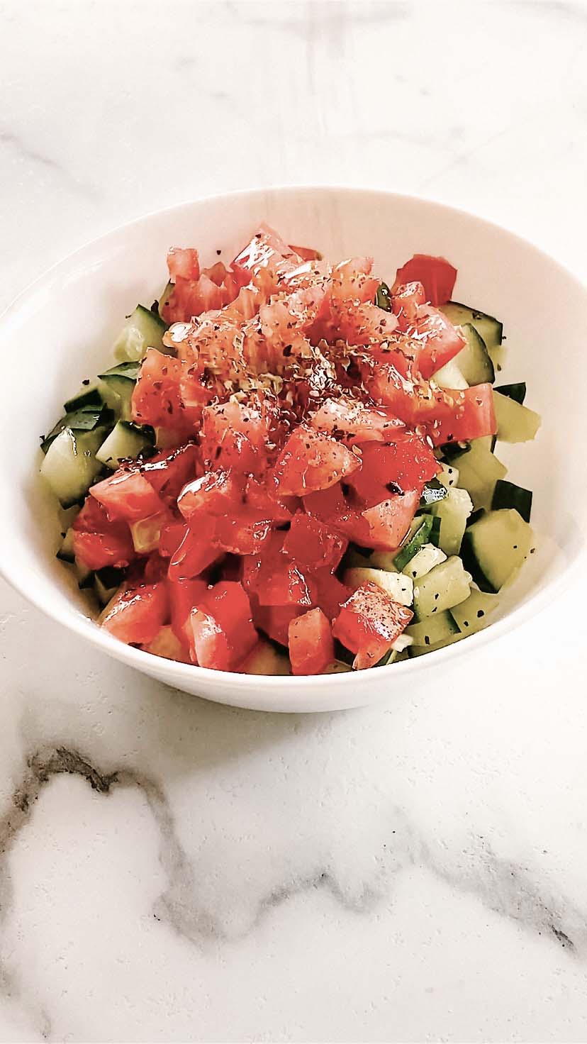A bowl with diced tomato and cucumber.