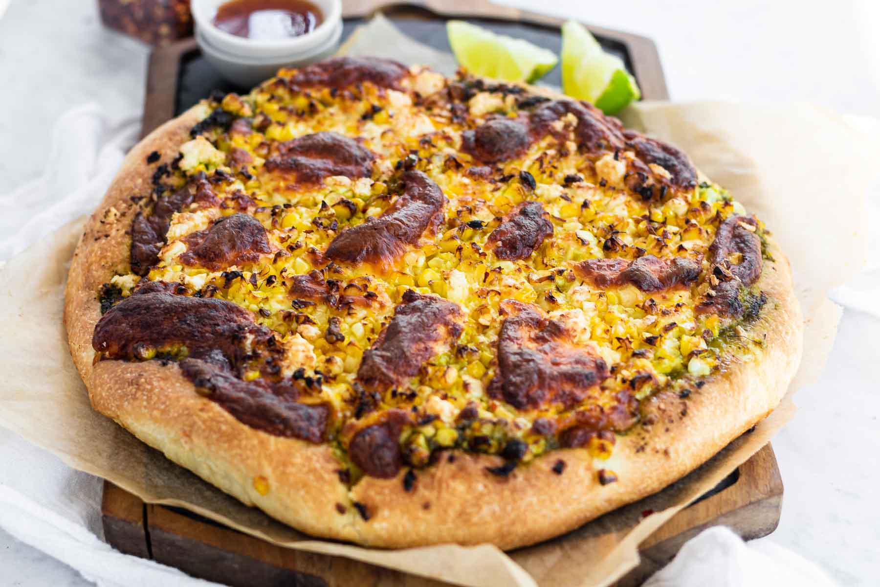A corn pizza on a slate platter.