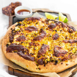 A corn pizza on a slate platter.