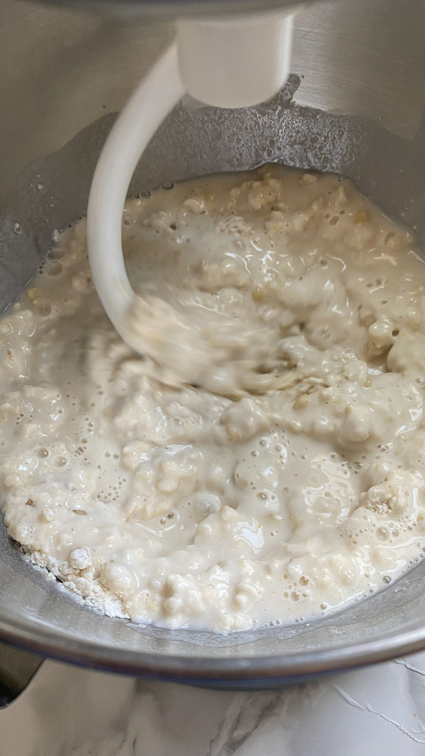 Mixing pizza dough in a stand mixer with a dough hook.
