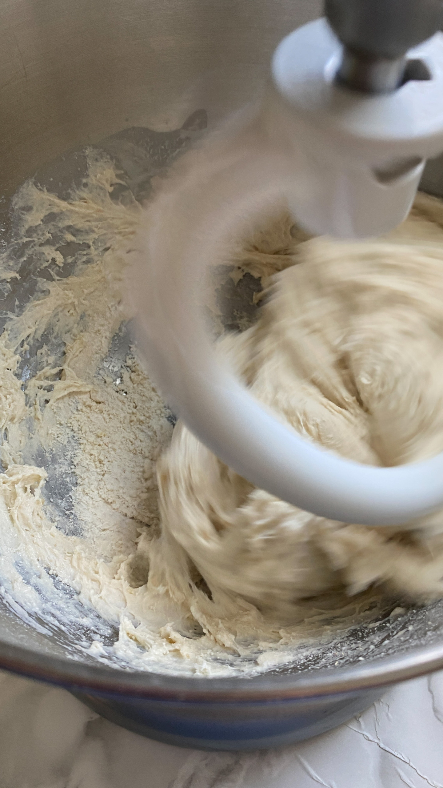 Mixing pizza dough in a stand mixer with a dough hook.
