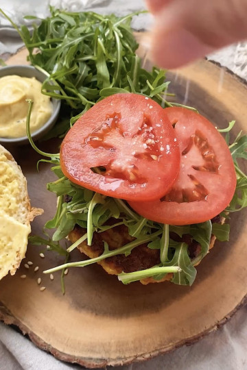 Tomato and arugula on top of a veggie burger.