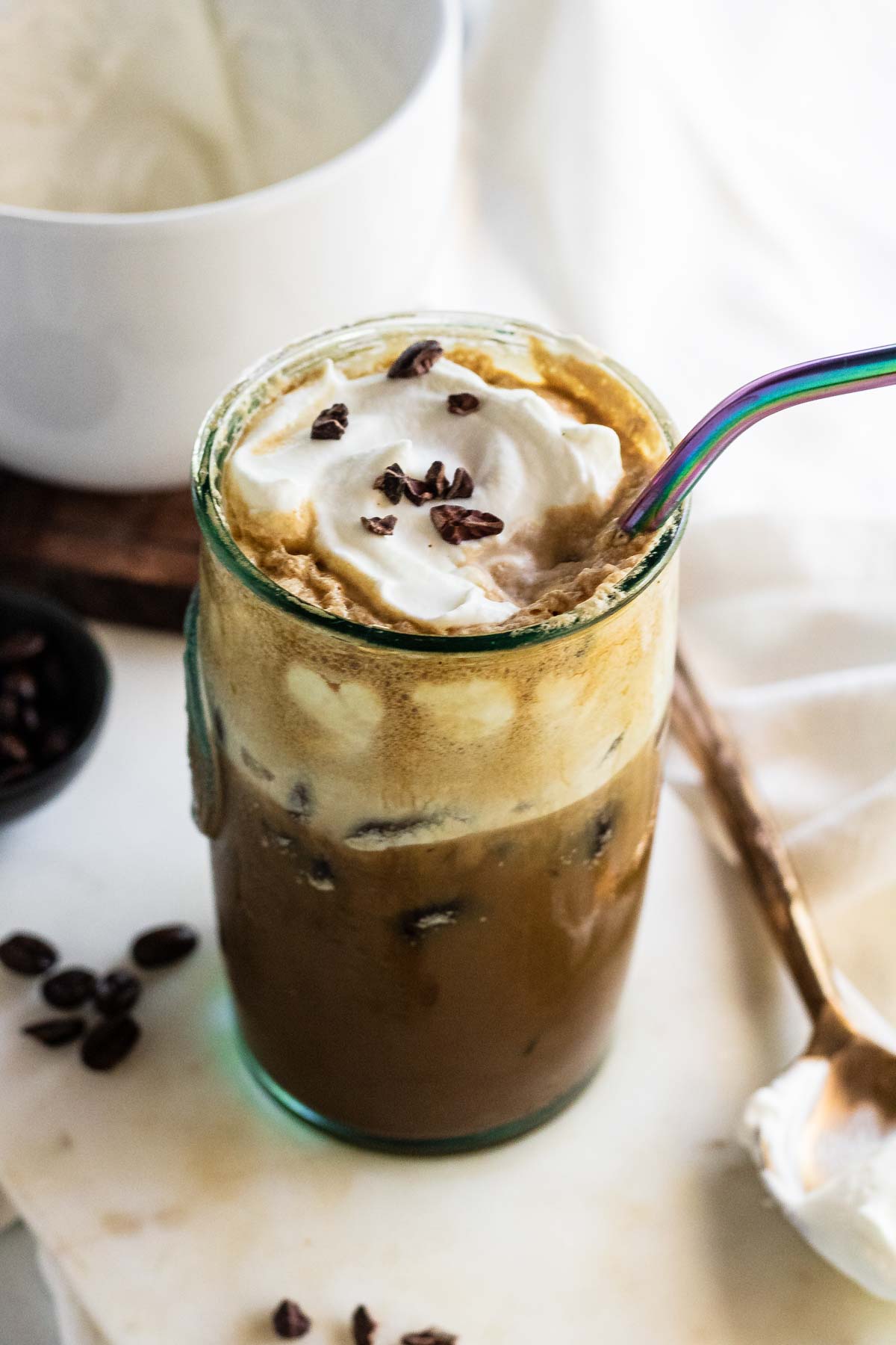 An iced coffee with whipped cream and cacao nibs on top.