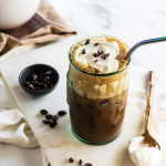 An iced coffee with whipped cream and cacao nibs on top.