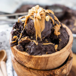 Chocolate peanut butter ice cream in a wooden bowl topped with peanut butter and peanuts.