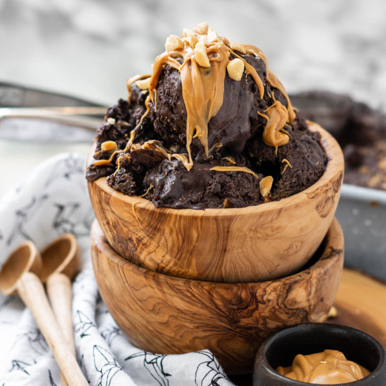 Chocolate peanut butter ice cream in a wooden bowl topped with peanut butter and peanuts.