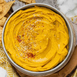 Yellow-orange hummus in a bowl.