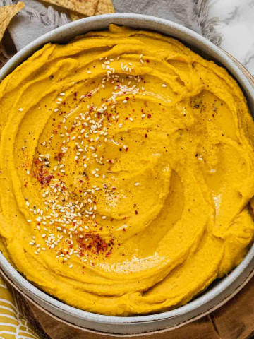 Yellow-orange hummus in a bowl.