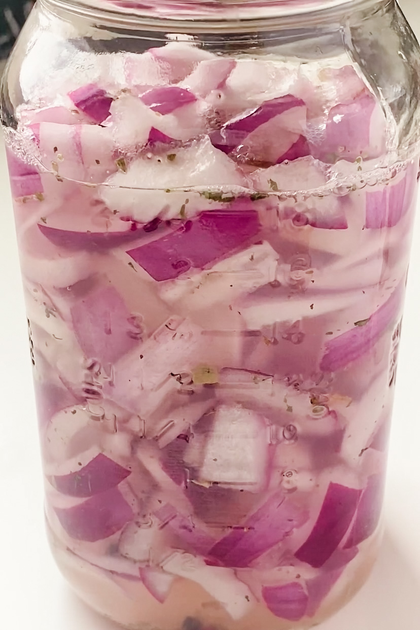 Sliced red onion in a jar of liquid.