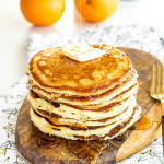 A stack of panckes with a pat of butter on top and syrup being poured on.