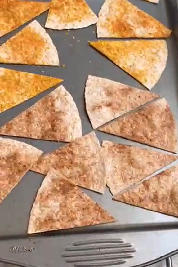 Flour tortilla triangles on a baking sheet for baking.