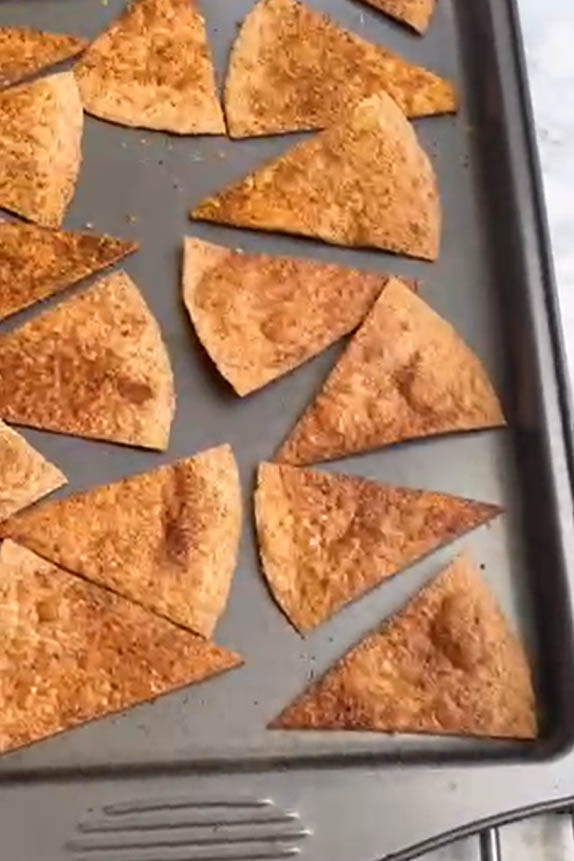 Baked flour tortilla triangles on a baking sheet.