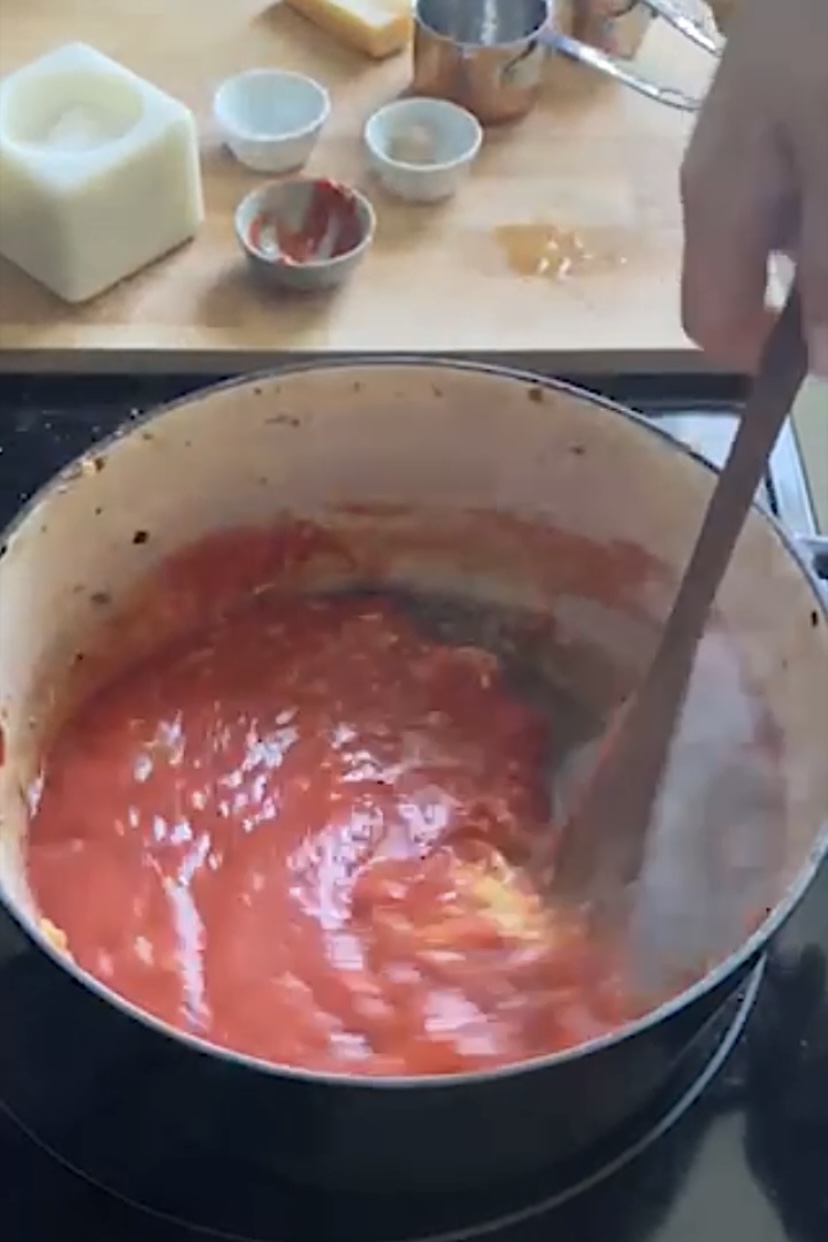 Stirring a red tomato sauce in a pot.