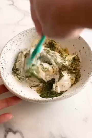 Mixing spices with yogurt, sour cream, and mayo in a bowl.