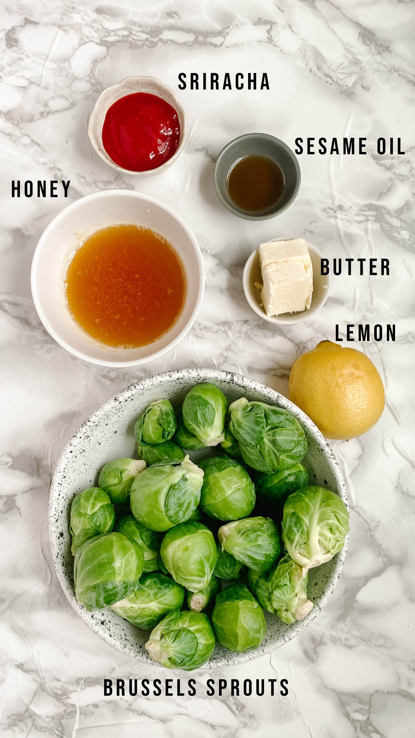 Ingredients for roasted Brussels sprouts on a white marble background.