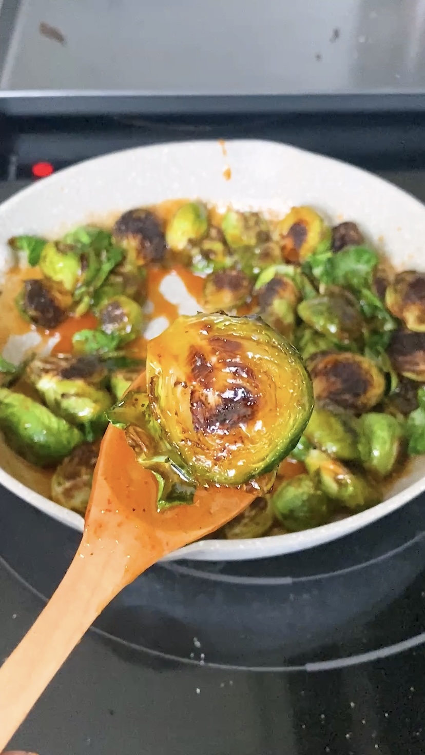 A close-up of a roasted Brussels sprout coated in honey sriracha sauce.