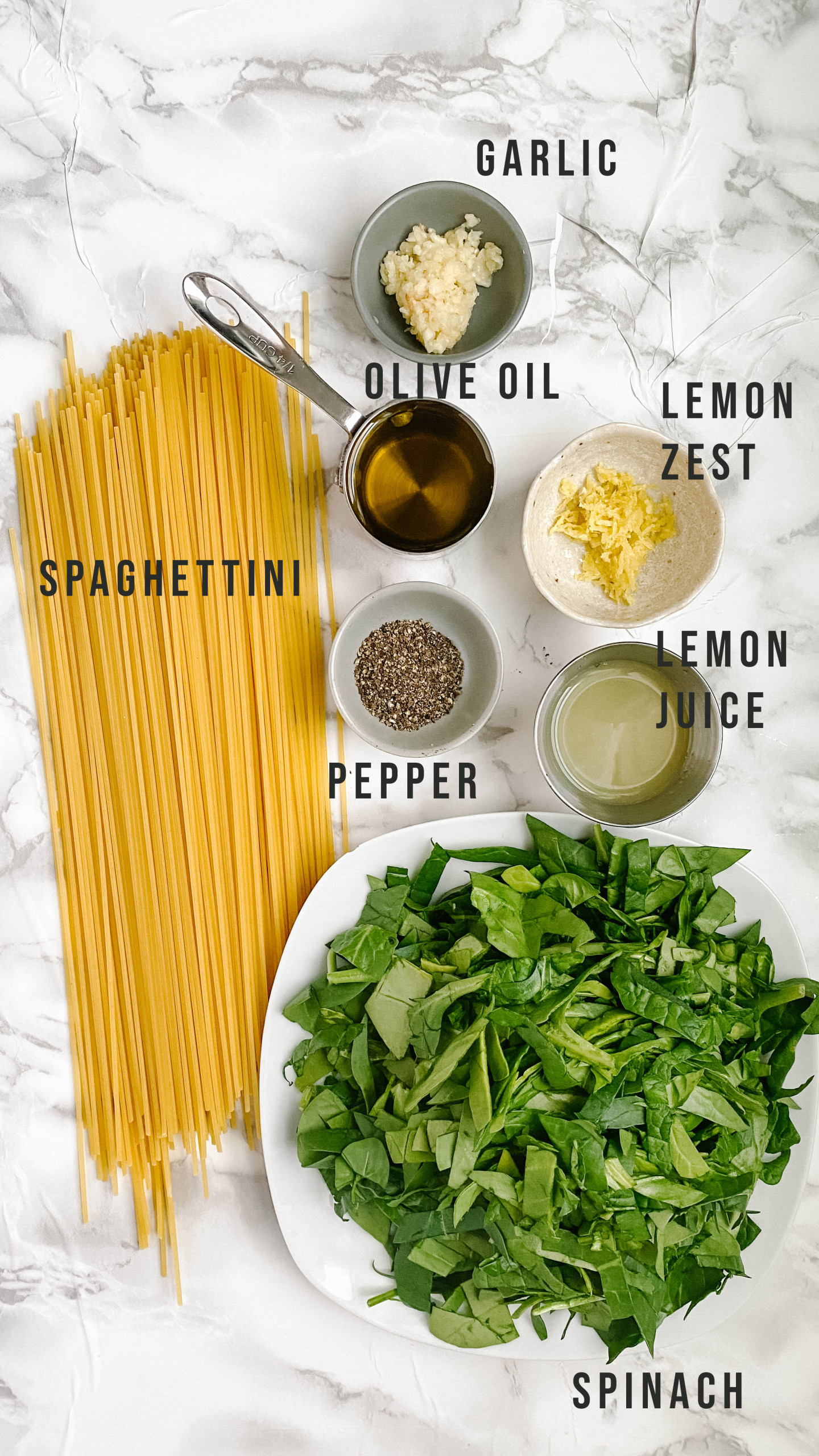 Ingredients for lemon pepper pasta on a white marble background.