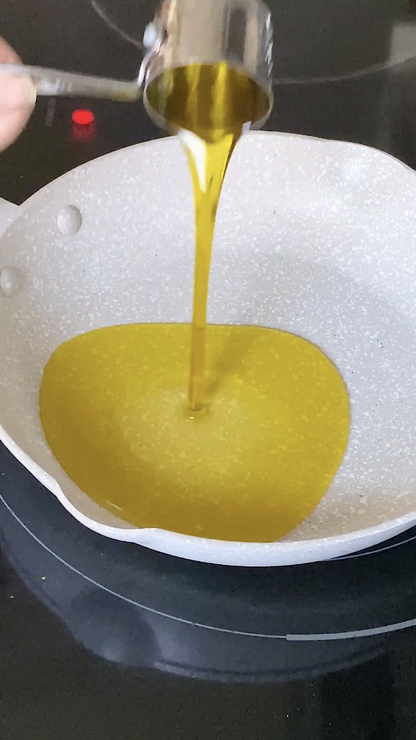 Pouring olive oil into a skillet.