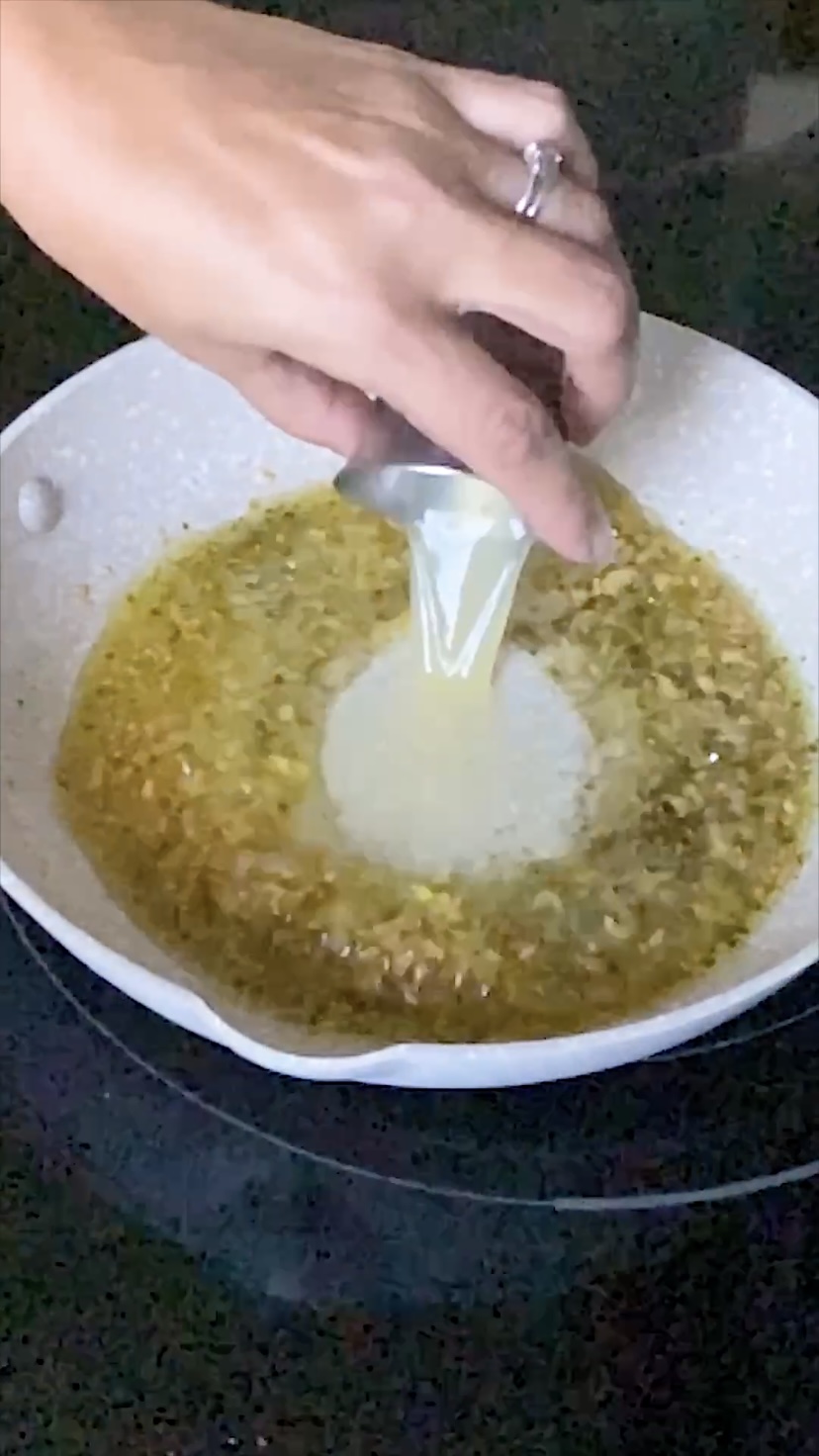 Adding lemon juice to olive oil and garlic in a skillet.