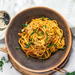 Noodles in a bowl topped with green onions.