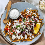 Fries topped with mushrooms, tomato, yogurt sauce, feta, and herbs.