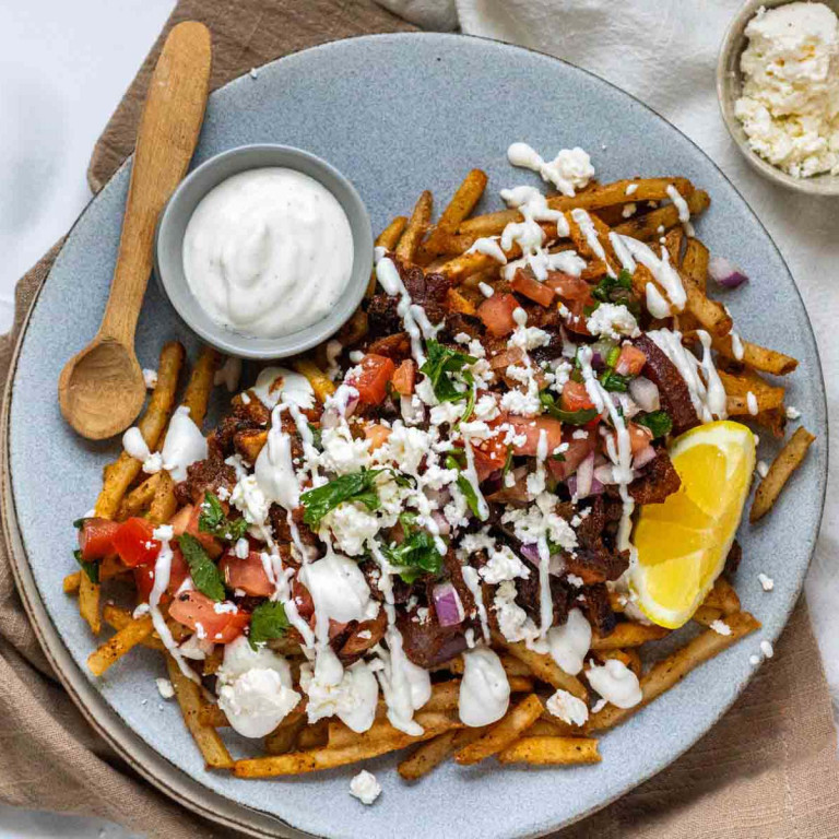 Fries topped with mushrooms, tomato, yogurt sauce, feta, and herbs.
