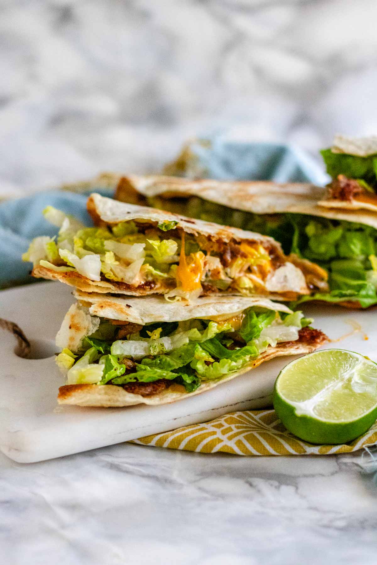 Quesadilla with cheese and lettuce on a white marble board.