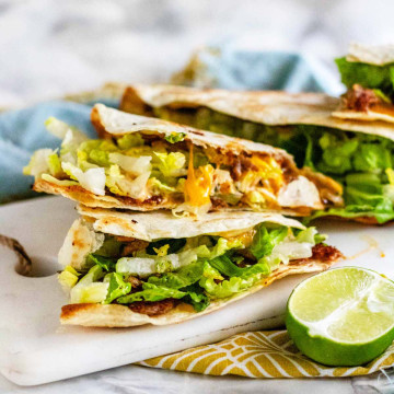 Quesadilla with cheese and lettuce on a white marble board.