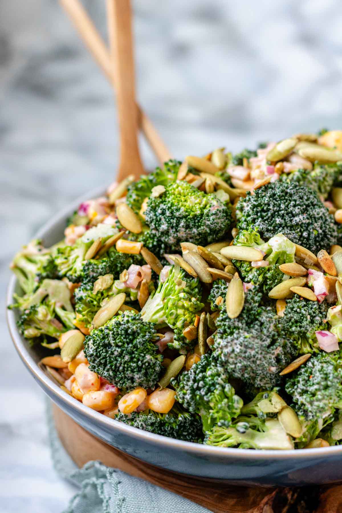 A bowl of broccoli, pepitas, and red onion coated in dressing.