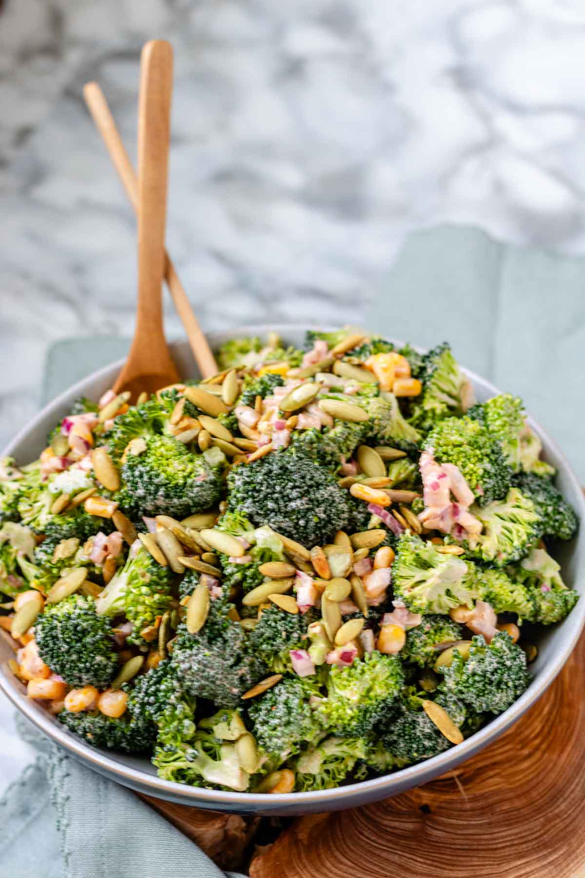A bowl of broccoli, pepitas, and red onion coated in dressing.