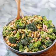A bowl of broccoli, pepitas, and red onion coated in dressing with text for Pinterest.